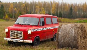 Punainen 1975 Ford Transit heinäpellolla