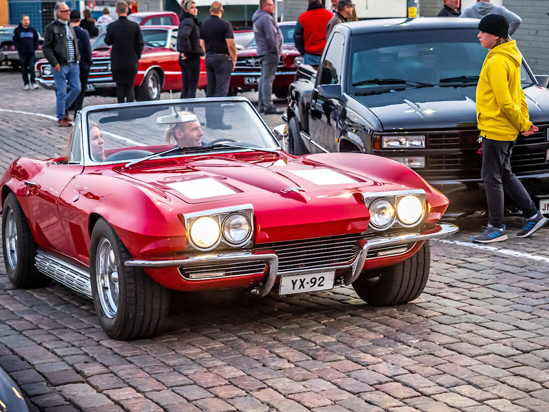 Nainen ja mies punaisessa 1963 Chevrolet Corvette Stingray jenkkiautossa