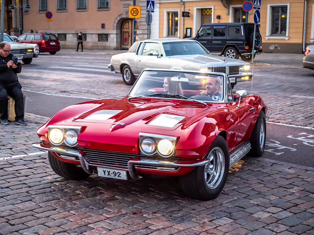 Nainen ja mies punaisessa 1963 Chevrolet Corvette Stingray urheiluautossa